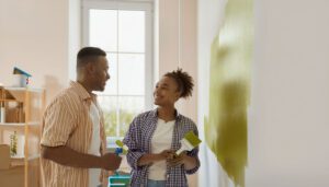 African man and woman painting a wall in their house.